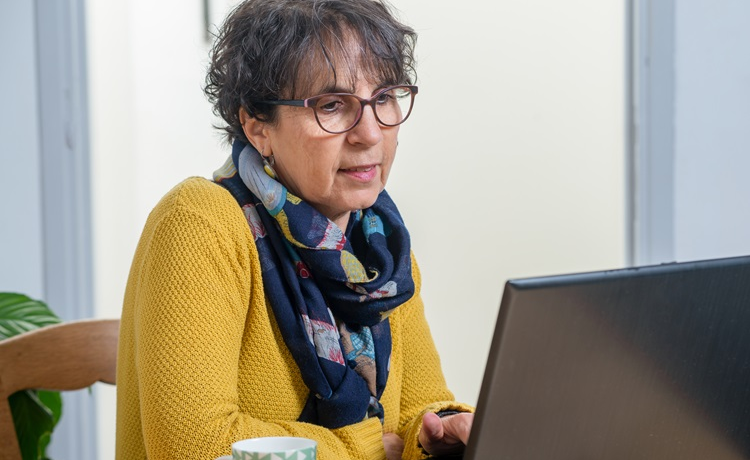Vrouw in gele trui met laptop